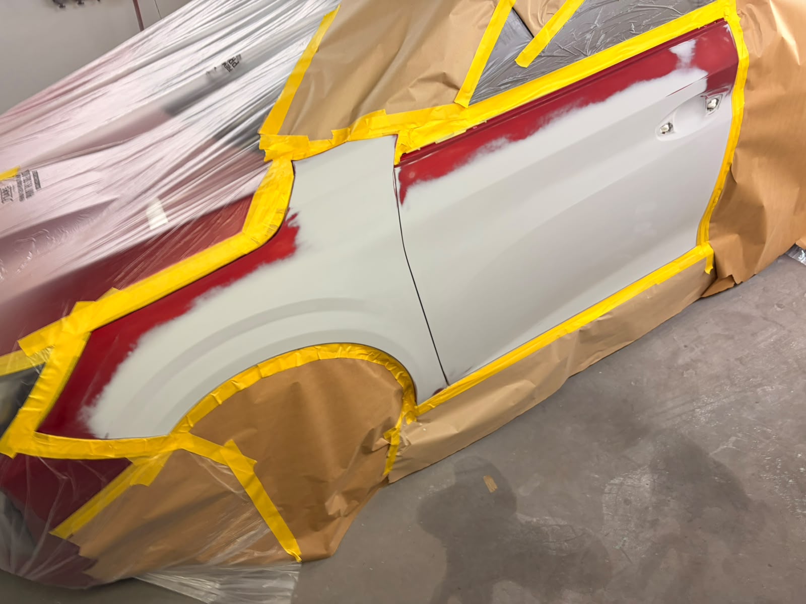 Red car side panel masked for paintwork in the workshop